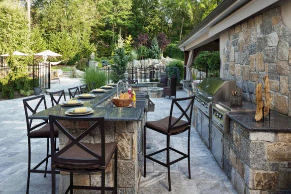 Luxury outdoor kitchen in the Hamptons with built-in grill, stone countertops, and custom masonry designTHE HAMPTONS, SECURITY SERVICES, LIGHTING SERVICES, LANDSCAPE SERVICES. EASTHAMPTON, SOUTHAMPTON, WESTHAMPTON, SAG HARBOR planting seasonal coastal