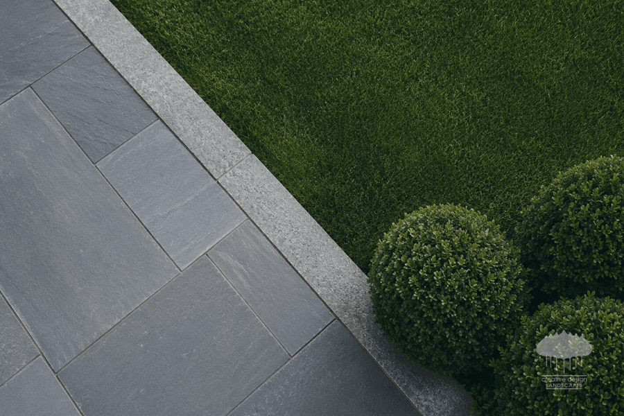 Season-Ready clean edge line between bluestone hardscape and manicured lawn