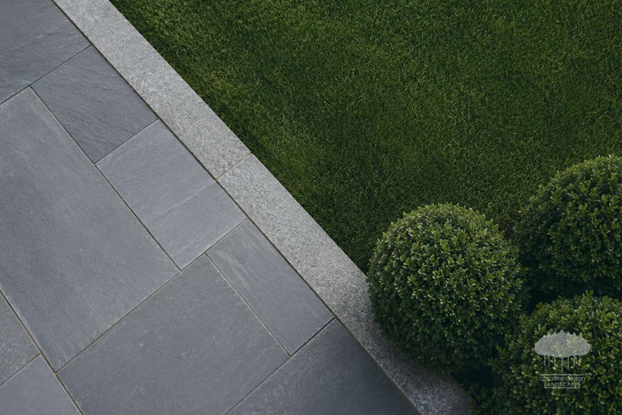 Season-Ready clean edge line between bluestone hardscape and manicured lawn