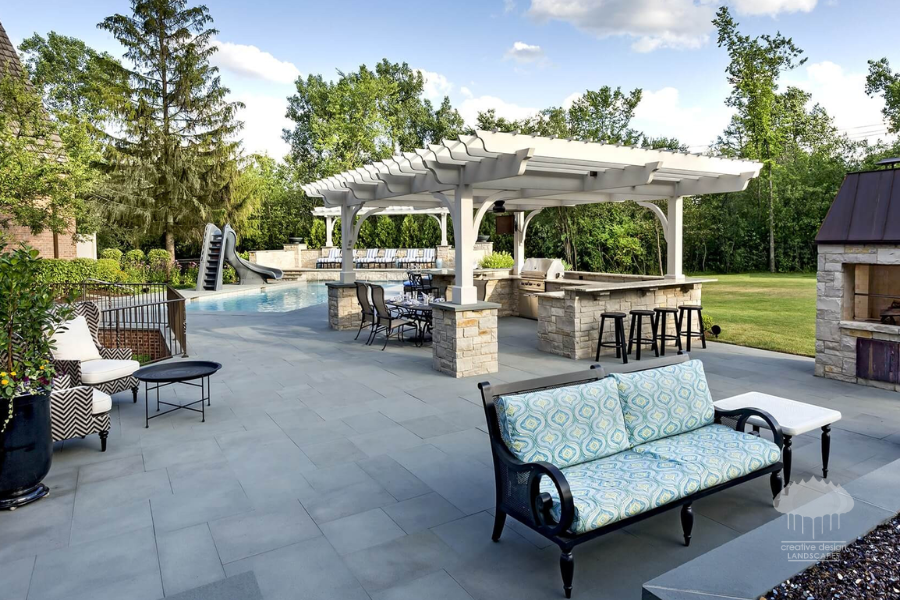 Hamptons hardscaping with a bluestone patio, pergola, and outdoor seating beside a pool