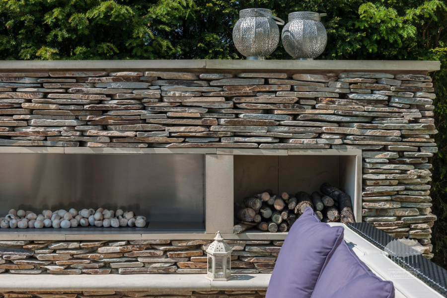 Stacked stone outdoor fireplace wall with built-in log storage and lounge seating