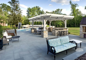 Hamptons hardscaping with a bluestone patio, pergola, and outdoor seating beside a pool